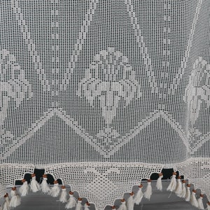 May include: White crocheted curtain with a delicate floral pattern and brown wooden beads along the bottom edge.