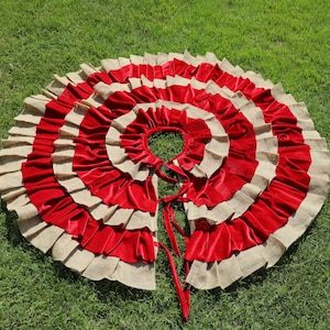 May include: A red and beige layered fabric circle with a ruffled edge. The fabric is gathered in the center to create a cone shape.