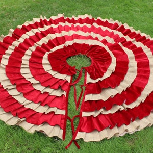 May include: A red and beige layered circle skirt with a ruffled design. The skirt is made of a soft, flowing fabric and has a simple, elegant style.