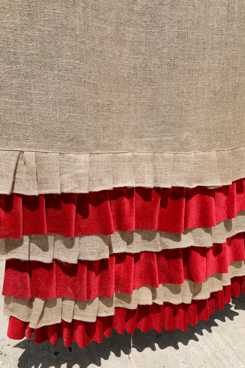 May include: A brown burlap fabric with a red velvet ruffle trim. The fabric has a woven texture and the ruffle is layered.
