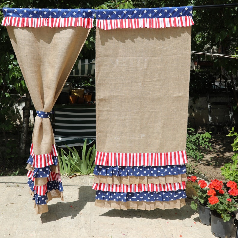 May include: Two burlap curtains with red, white, and blue ruffled trim. The trim features stars and stripes. The curtains are hanging from a rod.