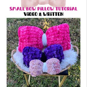 May include: A selection of bow-shaped pillows in shades of pink, purple, and peach, displayed in a woven basket. The pillows are crafted from a soft, textured fabric. The image includes the text "SMALL BOW PILLOW TUTORIAL VIDEO & WRITTEN".