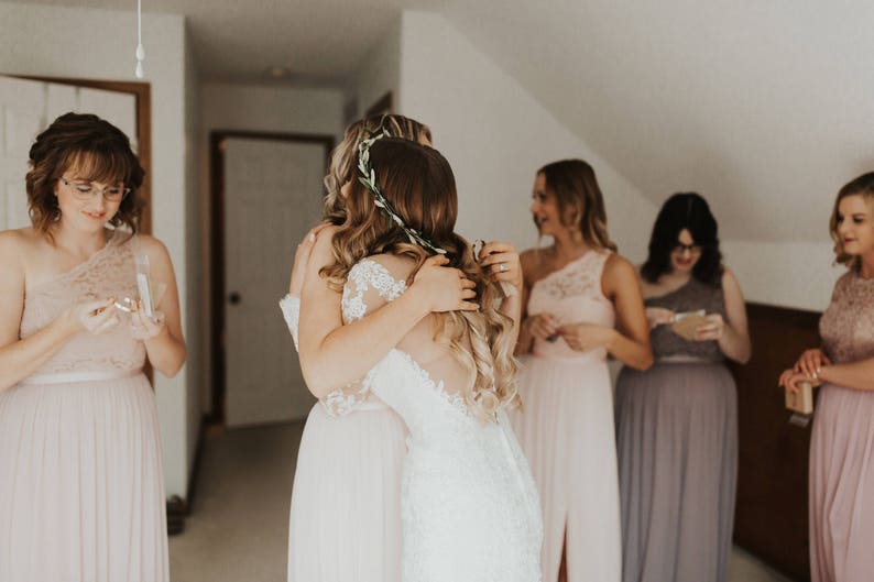 Maid of honor is hugging the bride after being gifted her personalized bracelet in a custom jewelry box. These make a meaningful gift that can be used after the wedding.