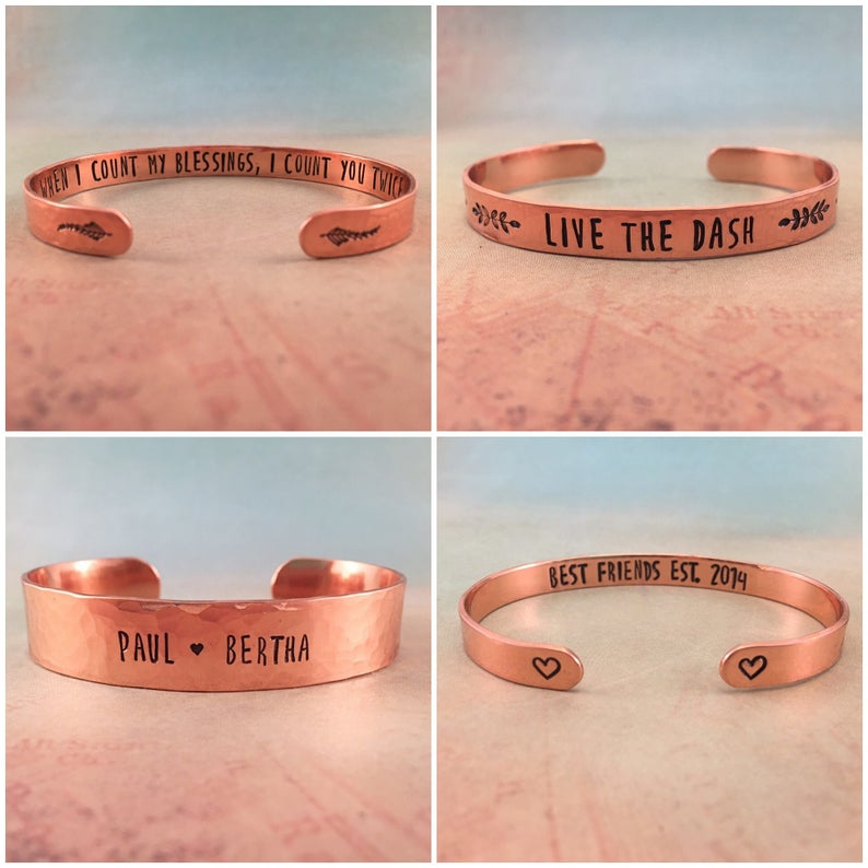 May include: Copper cuff bracelets with engraved text. One reads "WHEN I COUNT MY BLESSINGS, I COUNT YOU TWICE", another says "LIVE THE DASH", a third has "PAUL &hearts; BERTHA", and the last says "BEST FRIENDS EST. 2014" with hearts.