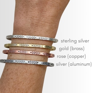 K&ouml;nnte beinhalten: Vier Metallarmreifen in Sterlingsilber, Gold (Messing), Ros&eacute; (Kupfer) und Silber (Aluminium). Jeder Armreif hat ein sich wiederholendes Blattmuster. Der Text zeigt die Metallart an.