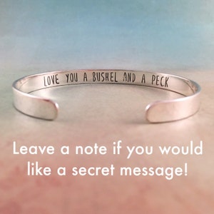 May include: Silver bangle bracelet with the inscription "LOVE YOU A BUSHEL AND A PECK".