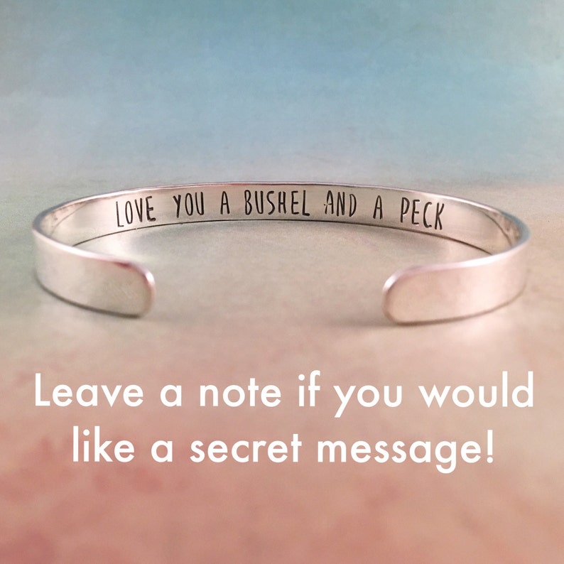 May include: Silver bangle bracelet with the inscription "LOVE YOU A BUSHEL AND A PECK".