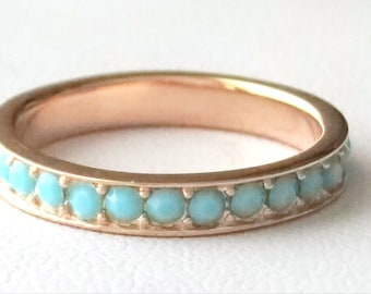 May include: A rose gold band ring with a row of turquoise stones.