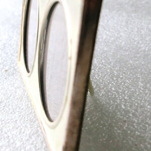 May include: A silver-toned double picture frame with two oval openings. The frame is made of metal and has a polished finish.
