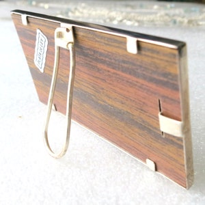 May include: A wooden picture frame with a silver metal frame and a silver metal stand. The frame has a label on the back that says "PLAT-O-LEY".