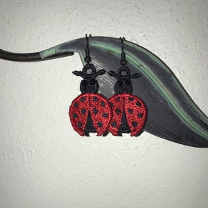 May include: A pair of black dangle earrings with red and black ladybug charms.