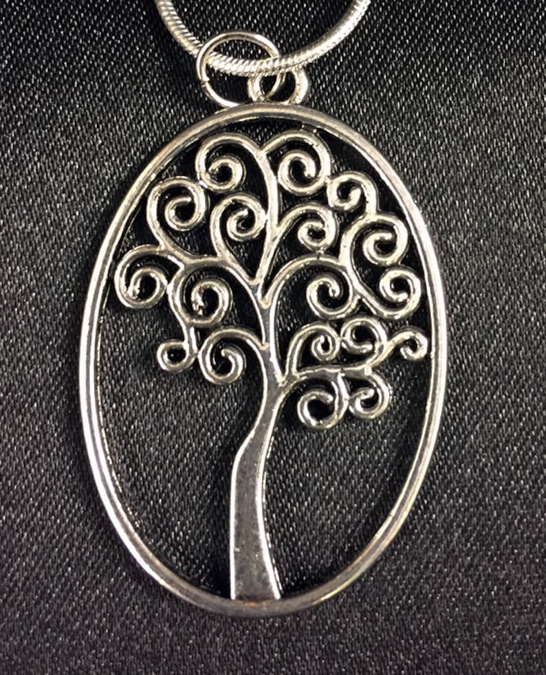 May include: A silver oval pendant necklace featuring a tree of life design with intricate swirls and branches.