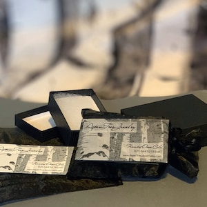 May include: A black velvet pouch with a white business card that reads "Aspen Tree Jewelry" and "Frances Owen Cole". The pouch is next to a black box with a white interior and a second black box with a white interior.