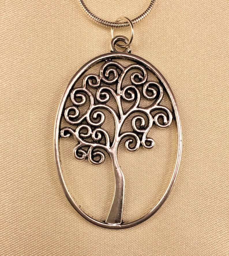 May include: A silver oval pendant necklace featuring a tree of life design with intricate swirls and branches.