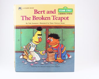 May include: A Sesame Street children's book titled "Bert and the Broken Teapot" featuring Bert and Ernie. The book cover shows Bert and Ernie in a kitchen setting, with Bert holding a broken piece of the teapot and Ernie holding a bag.