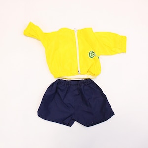 May include: A yellow and blue children's athletic outfit. The jacket has a zip and the text "Cabana" on the front. The shorts are navy blue.