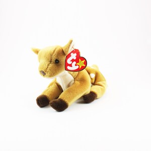 May include: A brown and white stuffed deer with a red Ty tag that says "Beanie Babies" and has a star on it.
