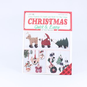 May include: A book titled "Christmas Quick & Easy" by Missy Becker. The cover features illustrations of Christmas ornaments and decorations, including a reindeer pulling a Santa Claus figure, a snowman, and a Christmas tree.