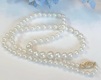 May include: A white pearl necklace with a gold clasp. The necklace features multiple strands of varying pearl sizes, with larger pearls in the center. The clasp is oval-shaped and has a decorative design.