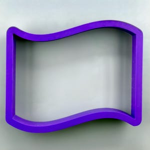 May include: A vibrant purple cookie cutter in the shape of a waving flag. The cutter has a rectangular form with a curved top edge, perfect for creating themed treats. The plastic material is smooth and the design is simple.
