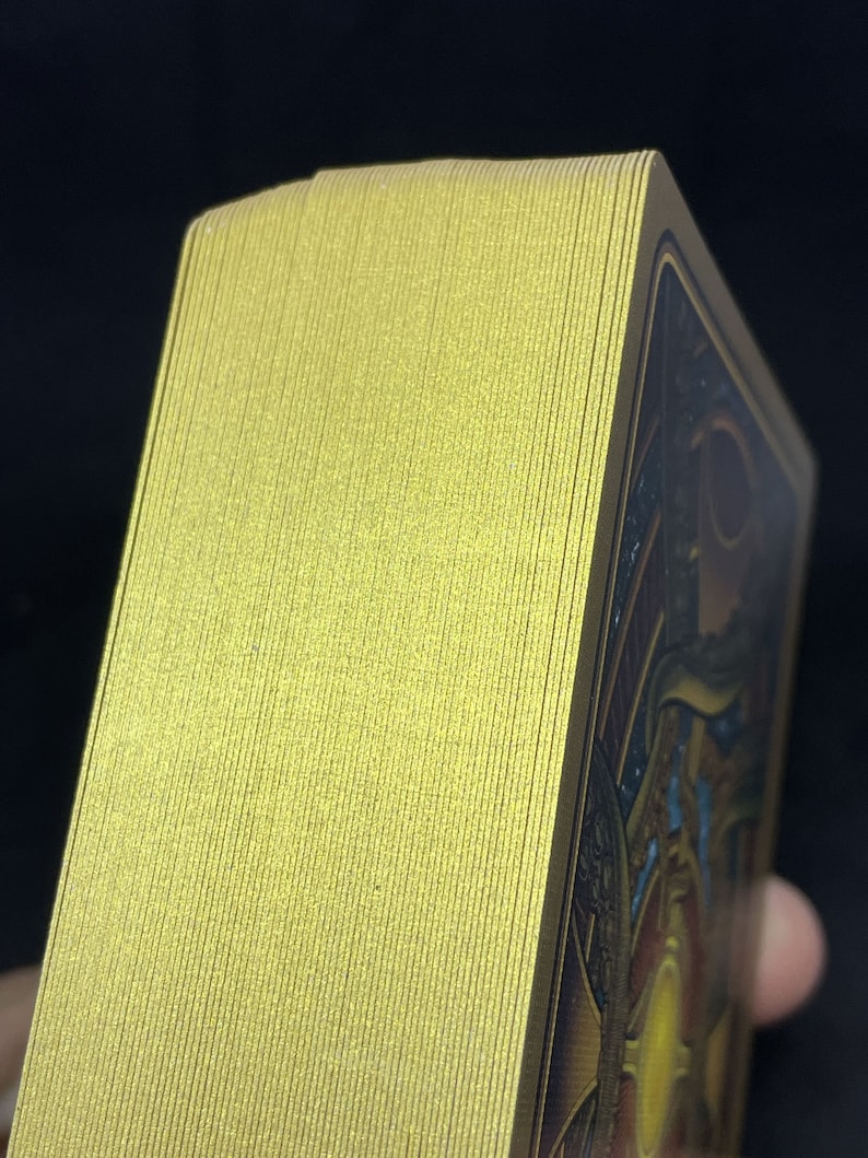 May include: A deck of playing cards with a gold foil finish. The cards are stacked neatly and the edges are visible.