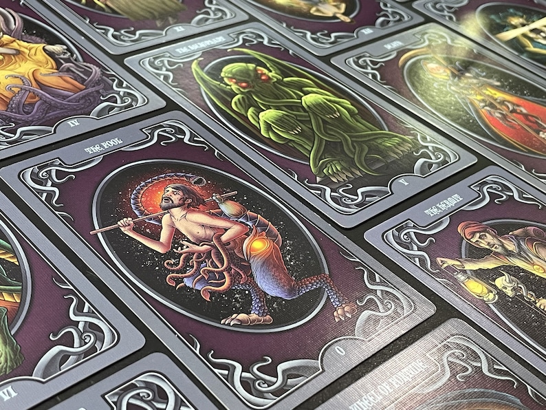 May include: A set of tarot cards with illustrations of various creatures and characters. The cards are purple with silver accents and feature ornate borders. The cards are numbered and have titles such as "The Fool" and "The Magician".
