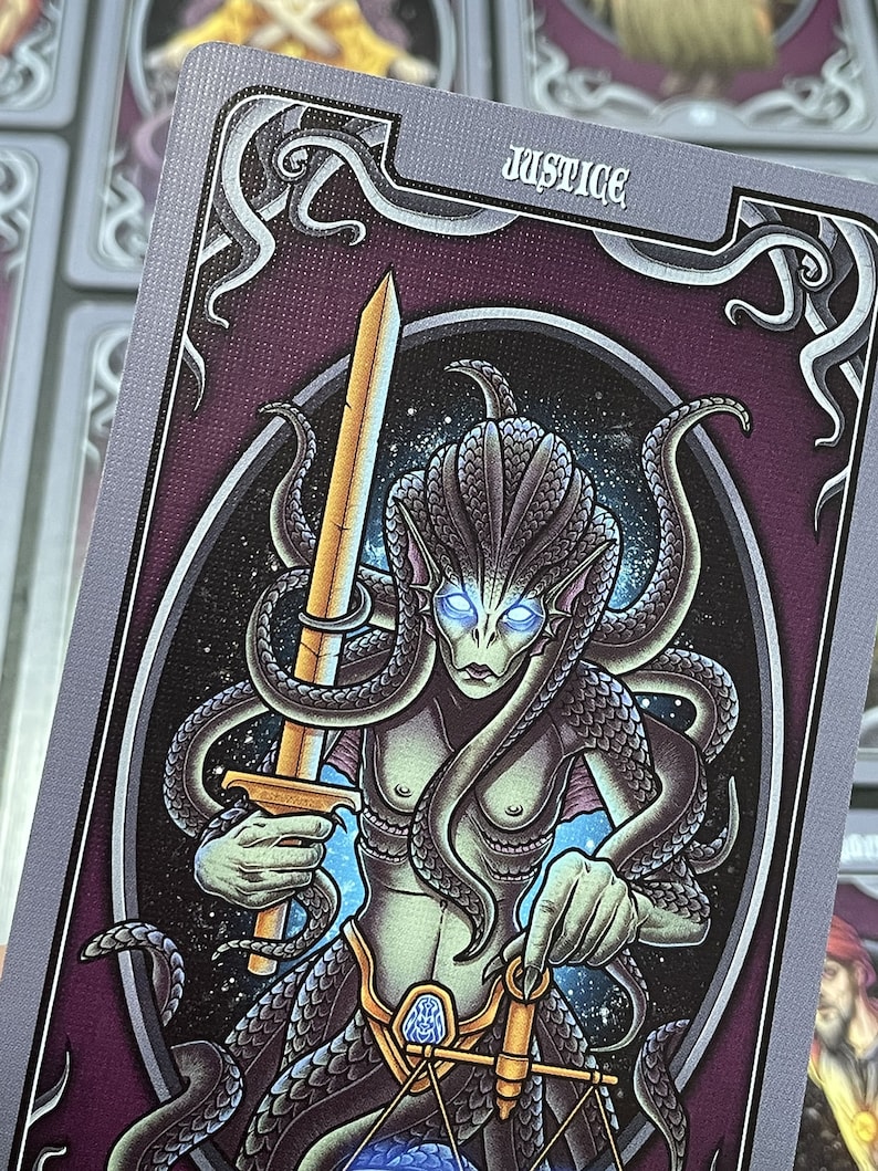 May include: A tarot card with a purple background and a silver border. The card depicts a green-skinned creature with a long, flowing tail and a sword in one hand and a scale in the other. The card is titled "Justice".