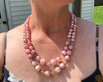 May include: A double strand pink and white glass bead necklace with gold accents. The beads are round and have a marbled effect.
