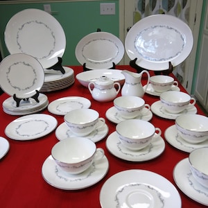 May include: A set of white china dinnerware with a delicate silver floral pattern. The set includes plates, bowls, cups, and saucers.