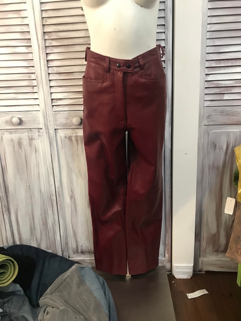 May include: A pair of burgundy leather pants with a high waist and a button fly.