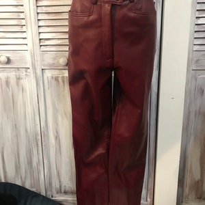 May include: A pair of burgundy leather pants with a high waist and a button fly.