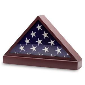 May include: A triangular wooden flag display case. The case is made of dark wood and features a glass front. Inside is an American flag with white stars on a blue background and red and white stripes.