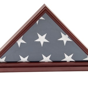 Könnte beinhalten: Ein hölzerner Flaggen-Präsentationskasten mit einer gefalteten amerikanischen Flagge im Inneren. Der Kasten ist dunkel mahagonifarben und hat eine dreieckige Form. Die Flagge ist durch ein klares Glasfenster sichtbar.