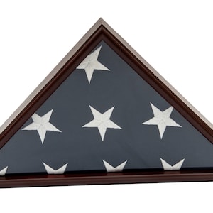 Könnte beinhalten: Ein Flaggen-Präsentationskasten aus Mahagoniholz mit einer gefalteten amerikanischen Flagge im Inneren. Der Kasten ist dreieckig und hat eine Glasfront.