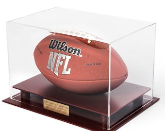 May include: A brown Wilson NFL football with white laces inside a clear acrylic display case on a dark wooden base. A gold plaque on the front reads: JOHN SMITH'S COLLECTION WILSON NFL GAME BALL PRESENTATION EDITION.