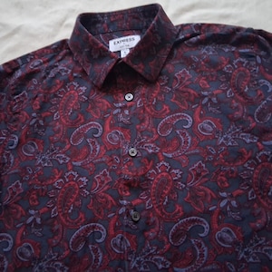 Puede incluir: Camisa abotonada con estampado de cachemira en tonos azul marino y rojo. La camisa tiene cuello y el nombre de la marca "EXPRESS" es visible en la etiqueta. Hecha de un material suave y cómodo.