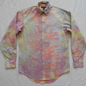 May include: A long-sleeved button-down shirt with a tie-dye pattern in shades of pink, yellow, and blue.