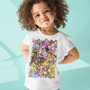 May include: A white t-shirt with a colorful graphic print of cartoon characters. The characters are all female and are from different animated shows. The shirt is being worn by a young child.