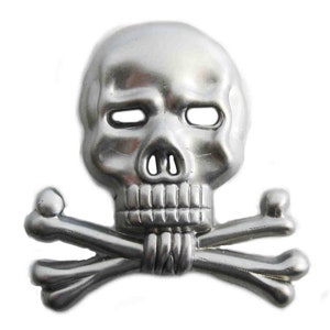May include: A silver-colored skull and crossbones emblem. The skull has empty eye sockets, a nose cavity, and a detailed jawline. The crossbones are positioned beneath the skull, creating a classic pirate or gothic design.