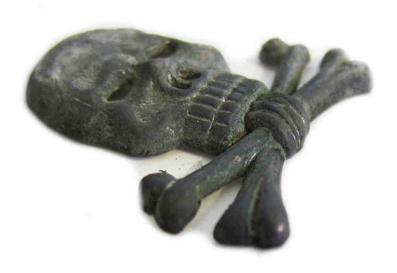 May include: A dark gray skull with crossbones, likely a decorative element. The skull has detailed features, including eye sockets and teeth. The crossbones are positioned behind the skull, creating a pirate or gothic theme.