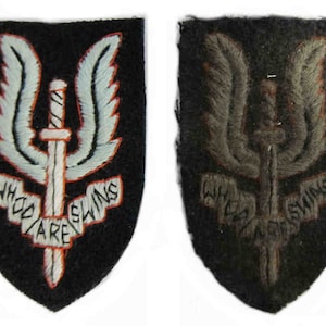 Peut inclure: Deux patchs brodés avec l'emblème du Special Air Service (SAS) britannique. L'emblème représente un poignard ailé avec les mots "Who Dares Wins" écrits autour. Un patch est noir avec des broderies blanches et orange, l'autre est noir avec des broderies brunes.