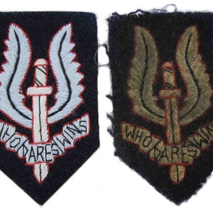 Peut inclure: Deux patchs brodés avec l'emblème du Special Air Service (SAS) britannique. L'emblème représente un poignard ailé avec les mots "Who Dares Wins" sur une bannière en dessous. Un patch est blanc et bleu, l'autre est vert et marron.