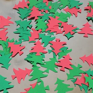May include: A pile of red and green paper Christmas tree cutouts. The cutouts are scattered on a silver surface.