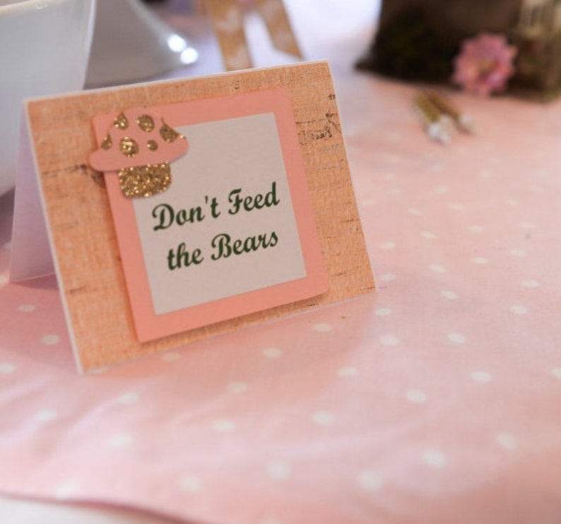May include: A pink and brown sign with a mushroom graphic and the text "Don't Feed the Bears".