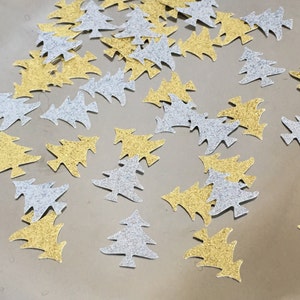 May include: A scattering of gold and silver glitter Christmas tree confetti. The confetti is in the shape of a Christmas tree.