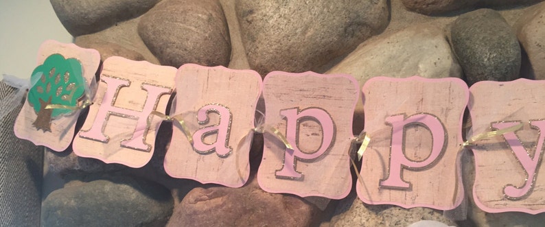 May include: Pink and gold glitter banner with the word "Happy" on it. The banner is made of cardboard and has a rustic look.