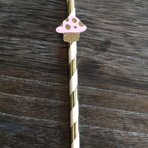 May include: Gold and white striped paper straw with a pink and gold glitter mushroom topper.