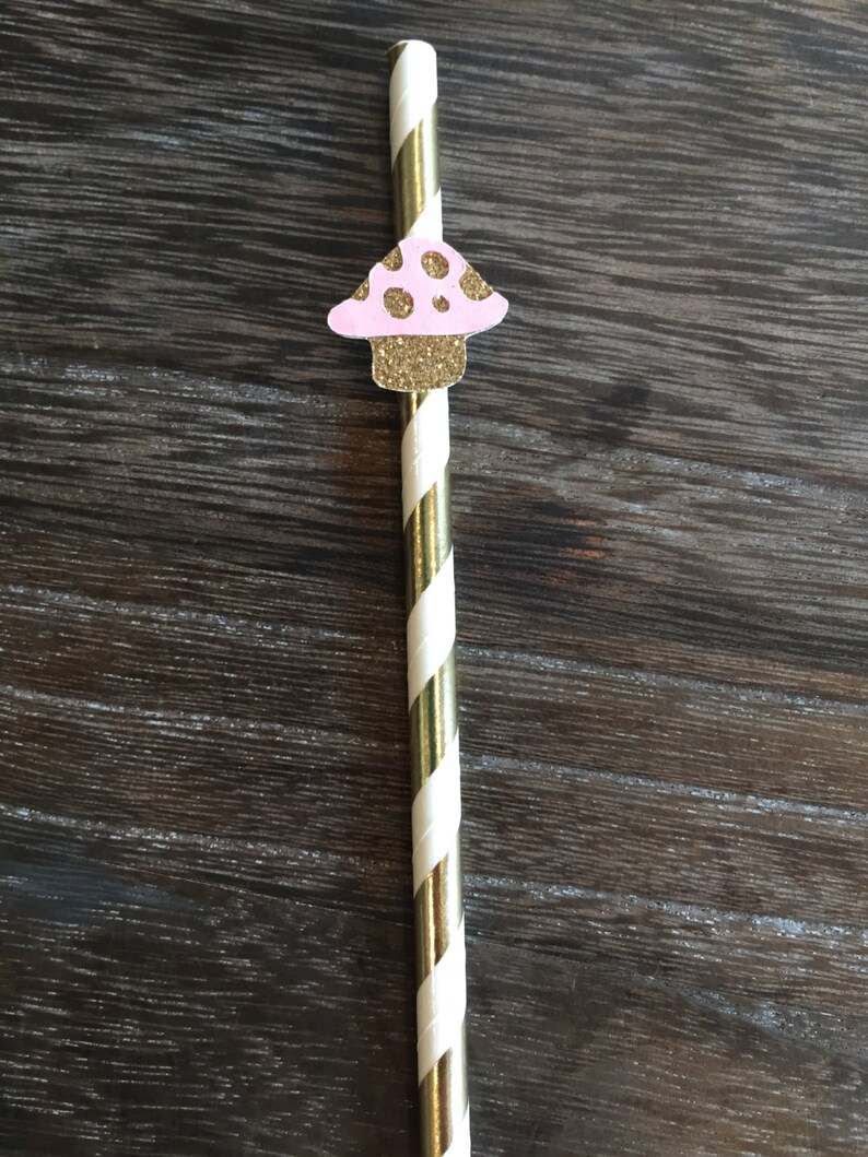 May include: Gold and white striped paper straw with a pink and gold glitter mushroom topper.