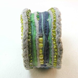 May include: A multi-colored braided bracelet with green, gray, and blue threads and yellow and green beads.