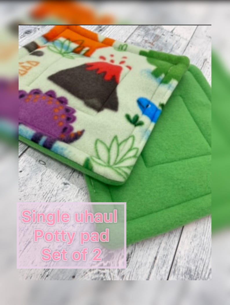 May include: A set of two square potty pads. One pad features a light green fleece fabric with a colorful dinosaur and volcano print. The second pad is solid green fleece. The text on the image reads: Single uhaul Potty pad Set of 2.